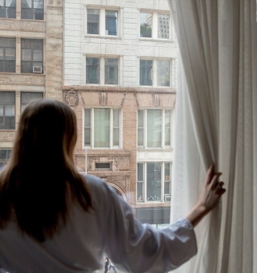 Woman looks through window at lower Manhattan buildings in New York.